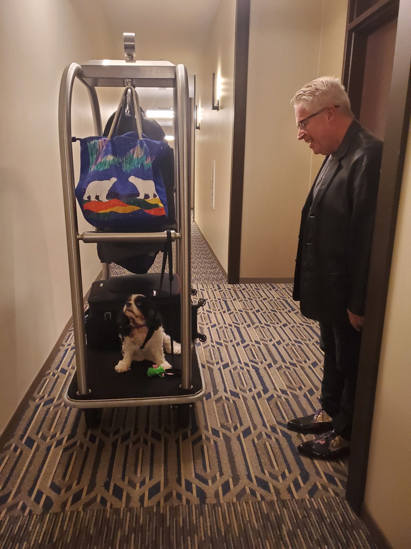 Peter Diedrich with a small dog on a hotel luggage cart