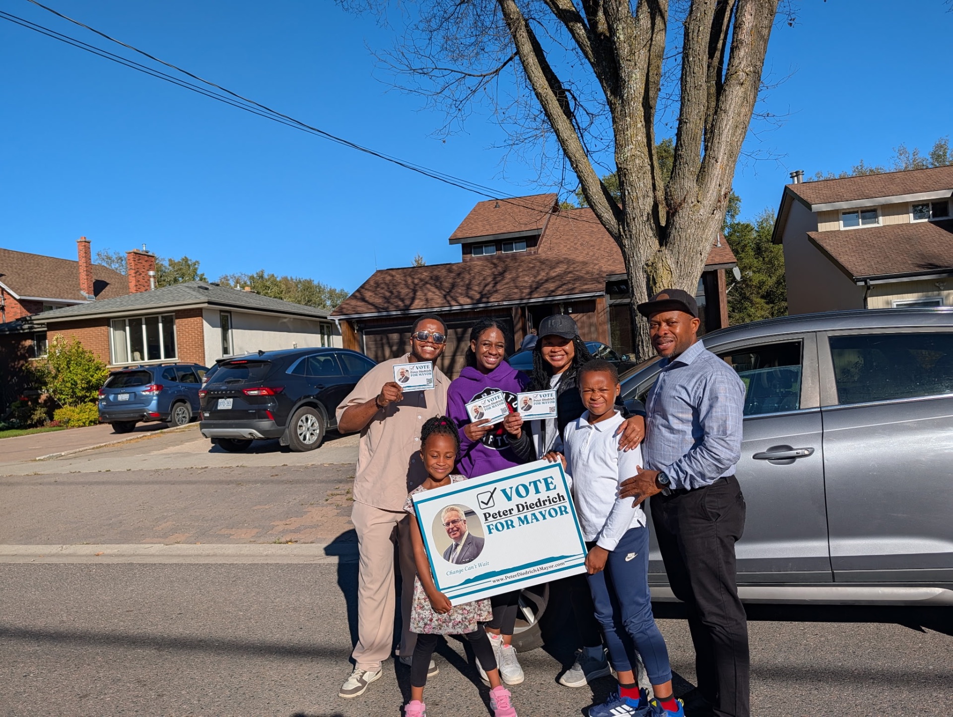 A family of supporters holding Vote Peter Diedrich for Mayor signs on a Thunder Bay street